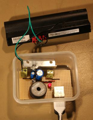 A circuit in a small plastic box connected to two USB leads and a small laptop battery